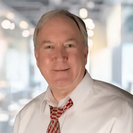 A man in a white shirt and red tie is smiling for the camera.
