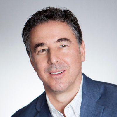 A man in a blue suit and white shirt is smiling for the camera