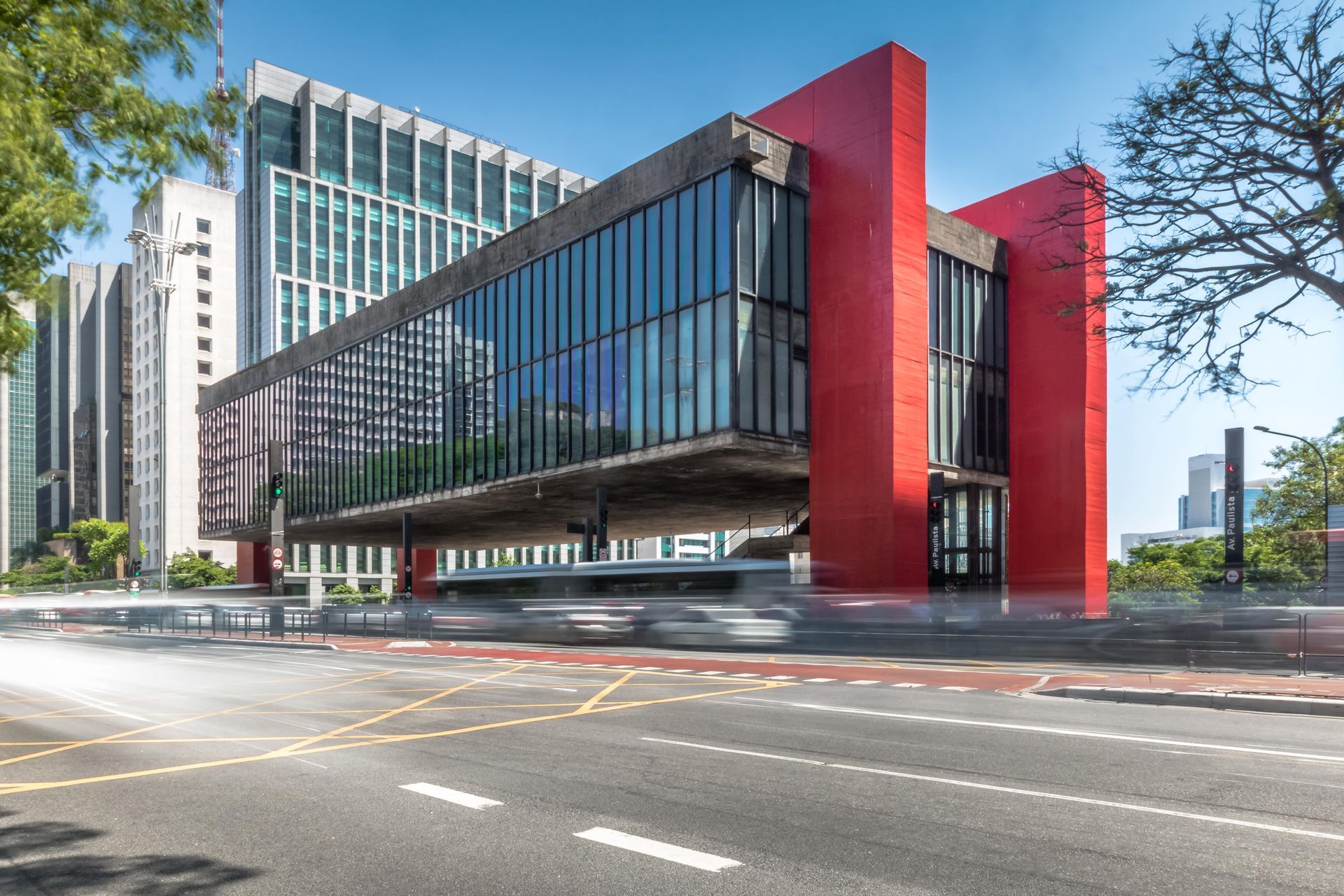 A large red building with a lot of windows is sitting on the side of a city street.