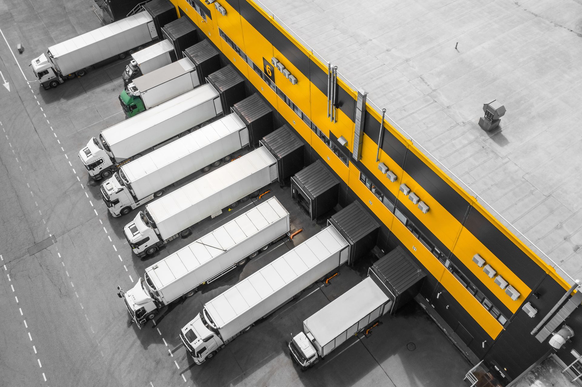 A row of orange trucks are parked in a parking lot.