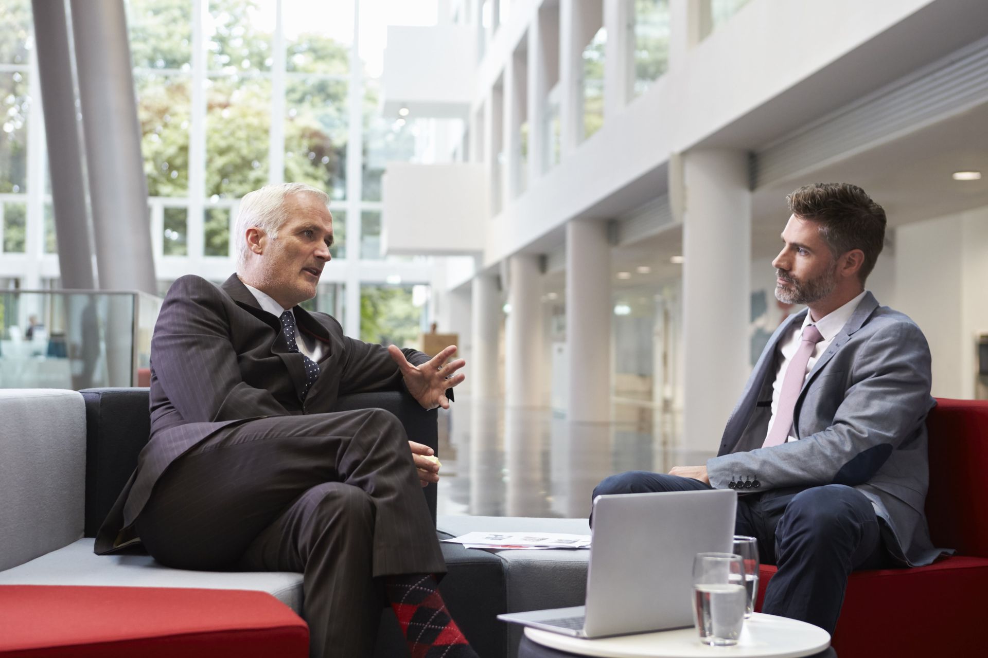 Two men are sitting on a couch having a conversation.