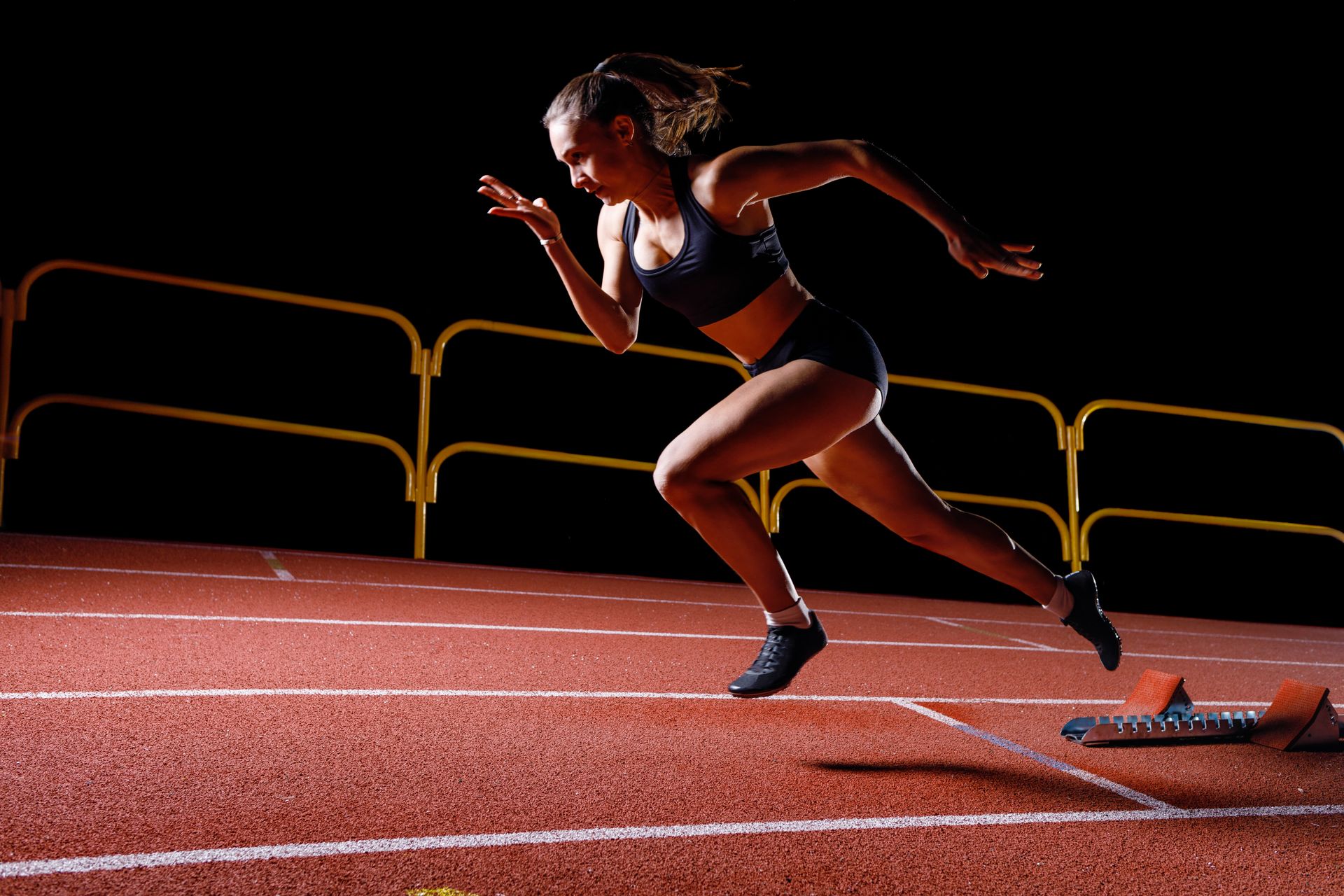 A woman is running on a track in the dark.