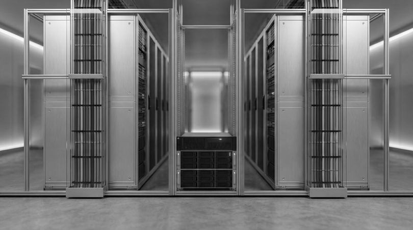 Symmetrical server room with rows of black data center racks and metallic glass doors