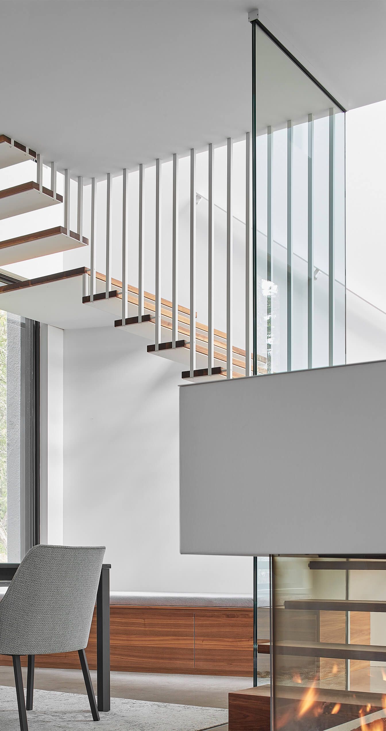 Intérieur moderne avec escalier en bois suspendu et cheminée.