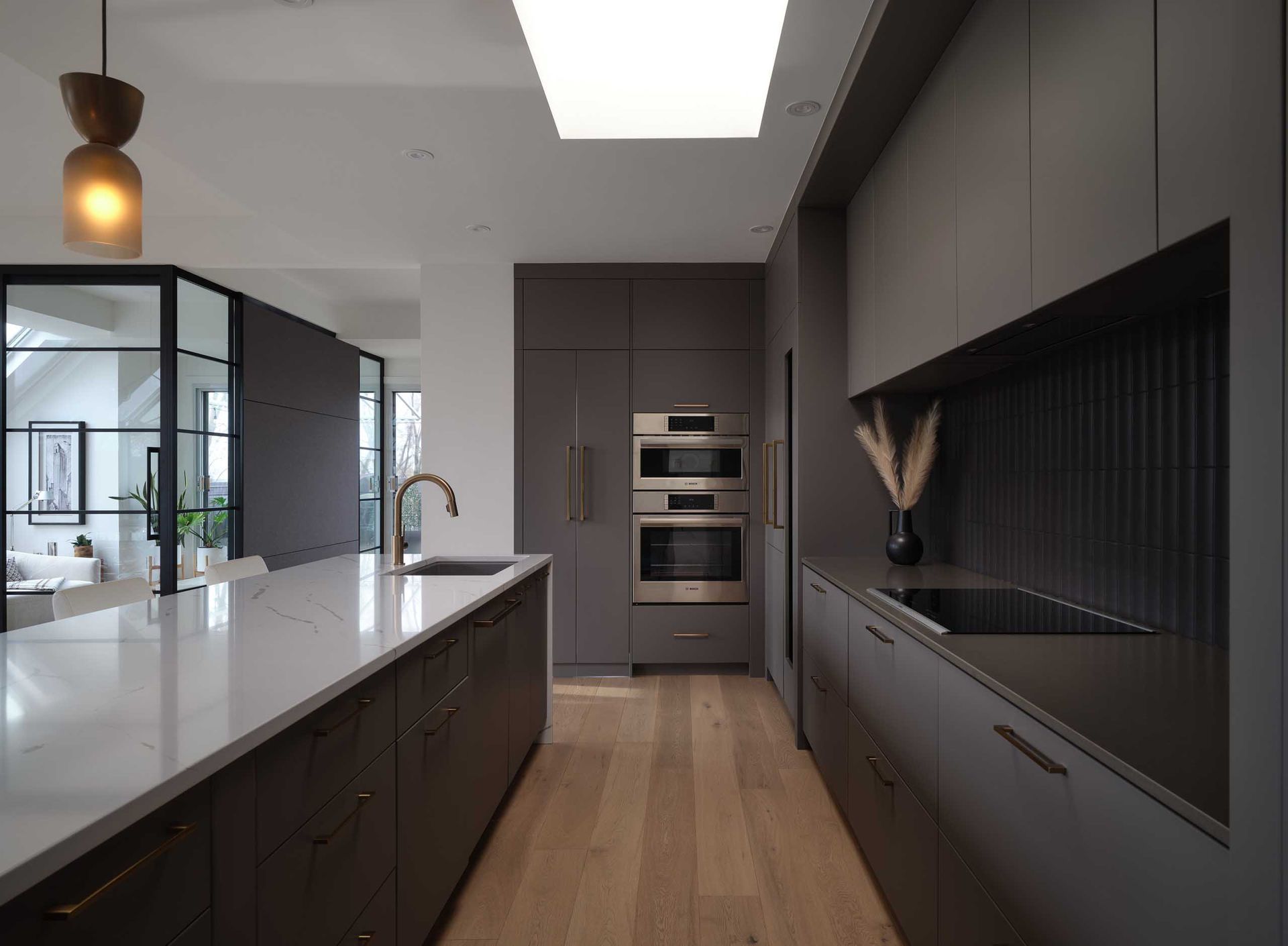 Cuisine moderne avec armoires grises, plancher en bois clair et &eacute;lectrom&eacute;nagers en acier inoxydable.
