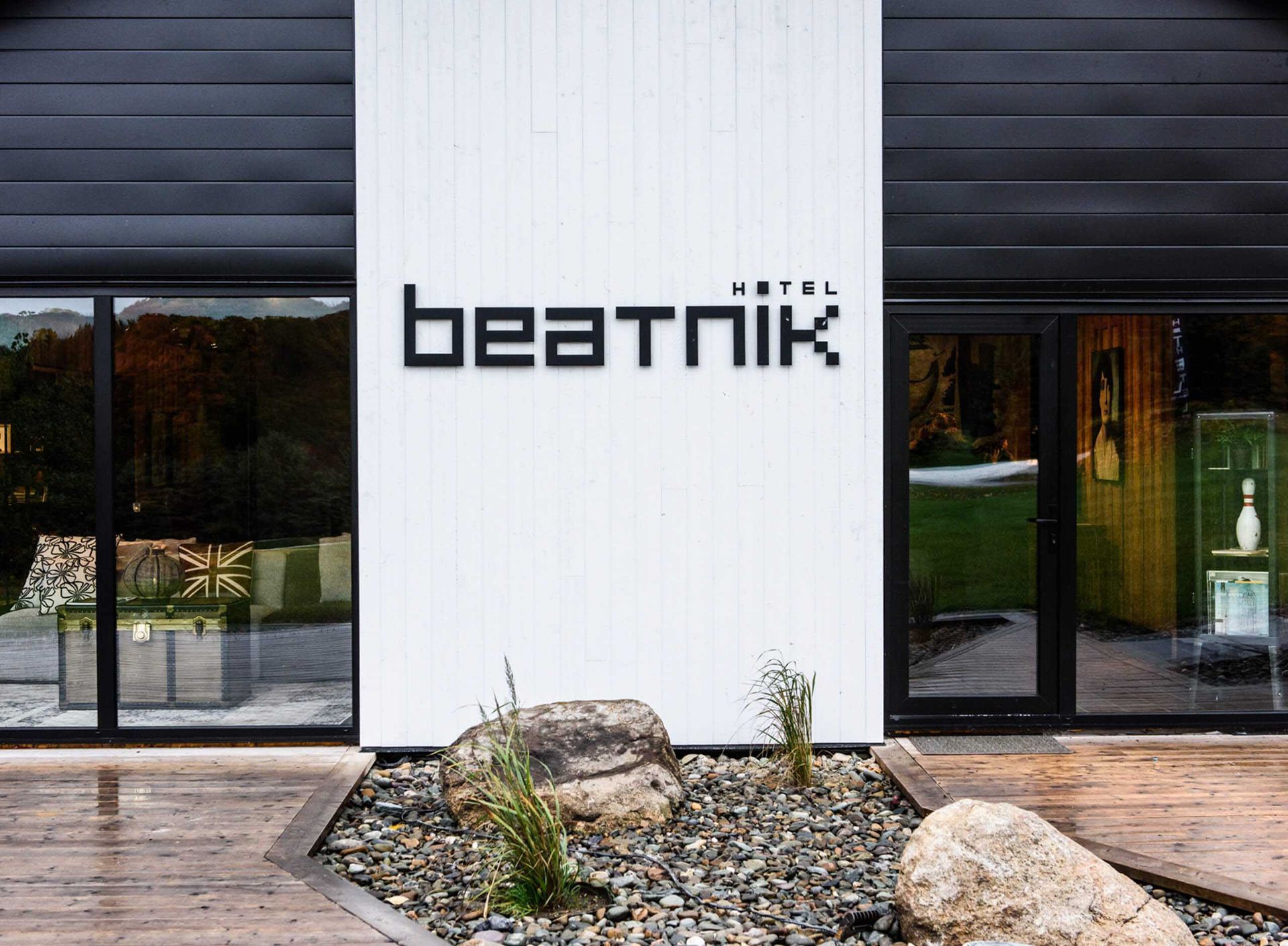 Enseigne de l'h&ocirc;tel Beatnik sur un mur blanc avec des bordures noires, des fen&ecirc;tres et un jardin de rocaille.