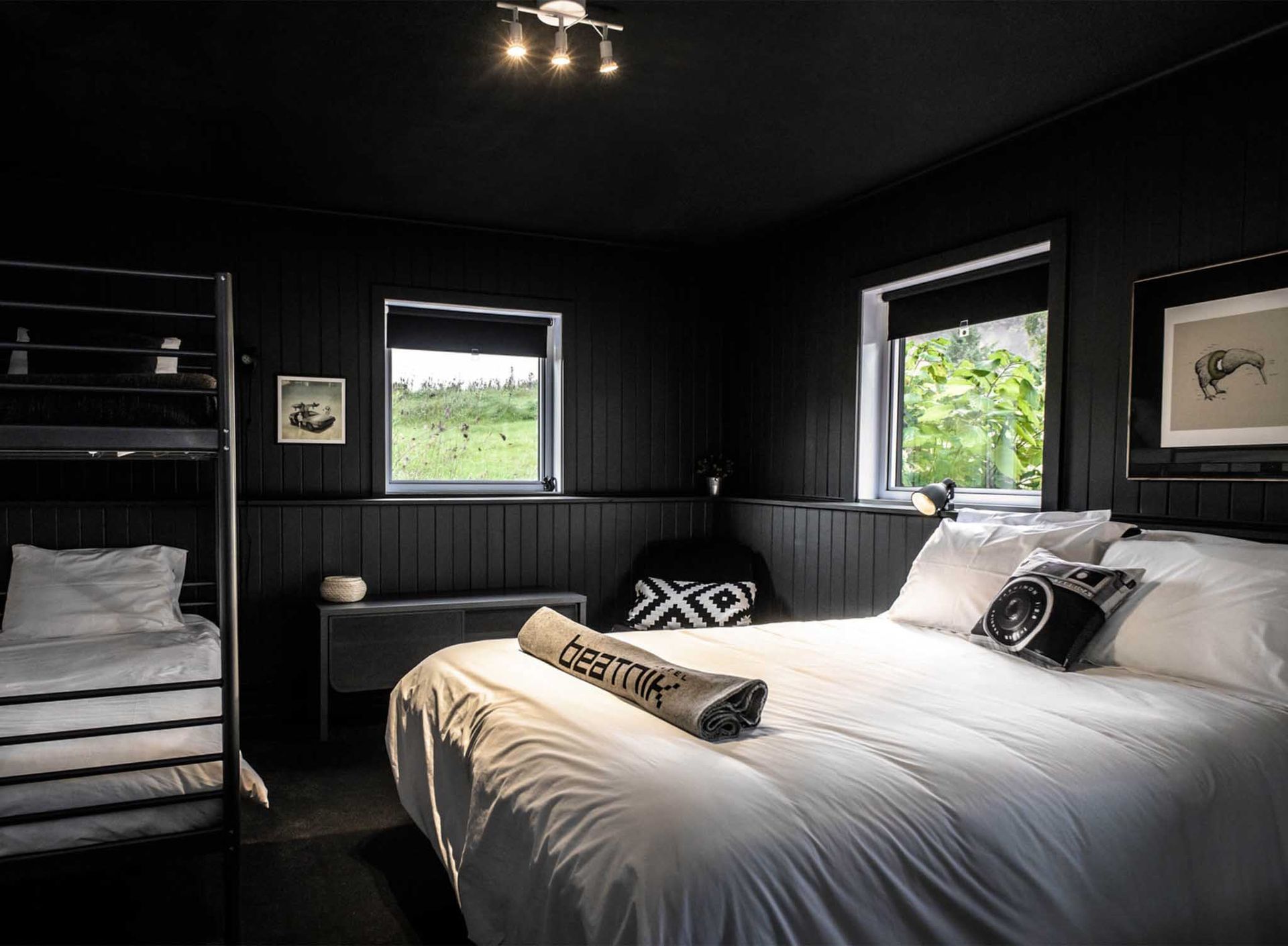 Chambre noire avec lit blanc, fenêtres et lits superposés ; un design minimaliste et moderne.