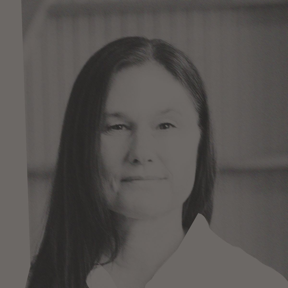Woman with long dark hair wearing a white collared shirt, smiling.