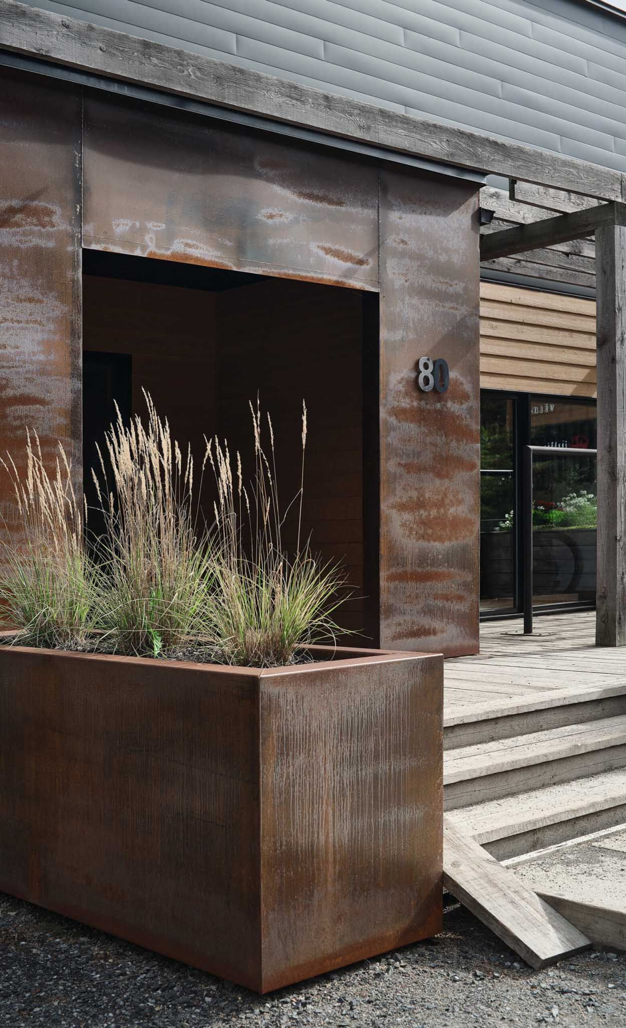 Weathered steel facade with planter box and entrance.