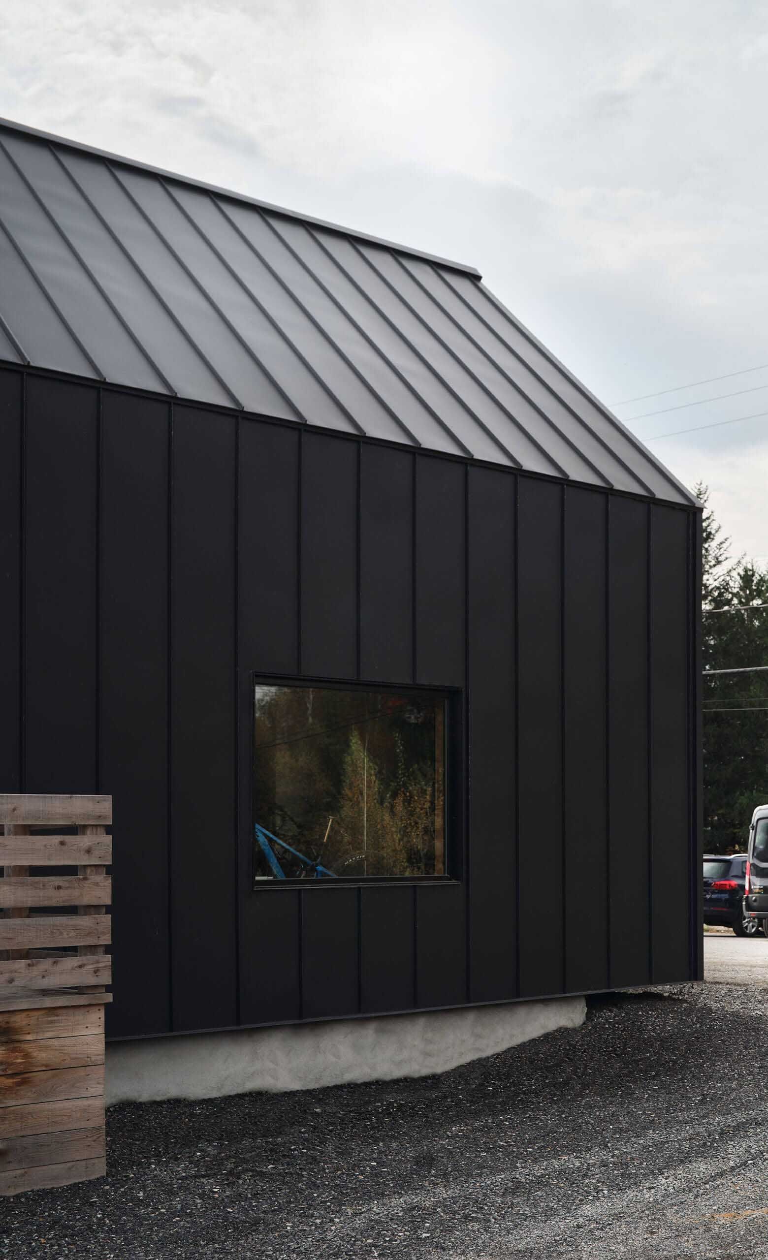 B&acirc;timent noir avec toit assorti et petite fen&ecirc;tre ; sol en gravier.