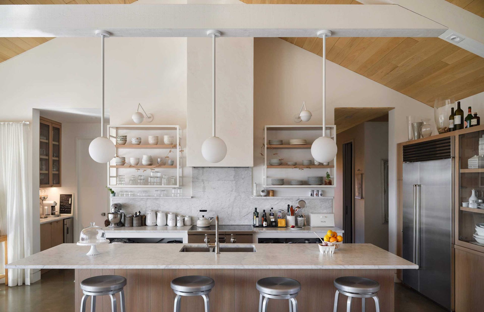 Cuisine moderne avec des touches de bois clair, des comptoirs blancs et des suspensions lumineuses en forme de globe.