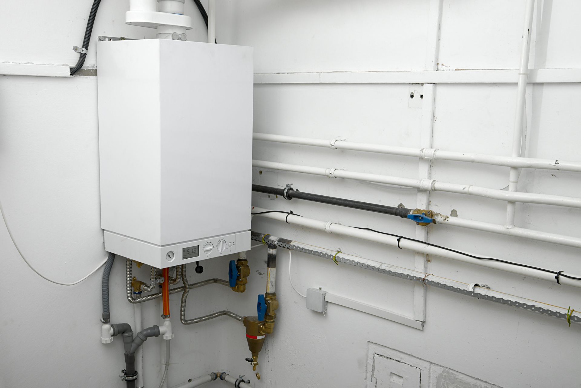 White wall-mounted gas boiler with pipes and valves.