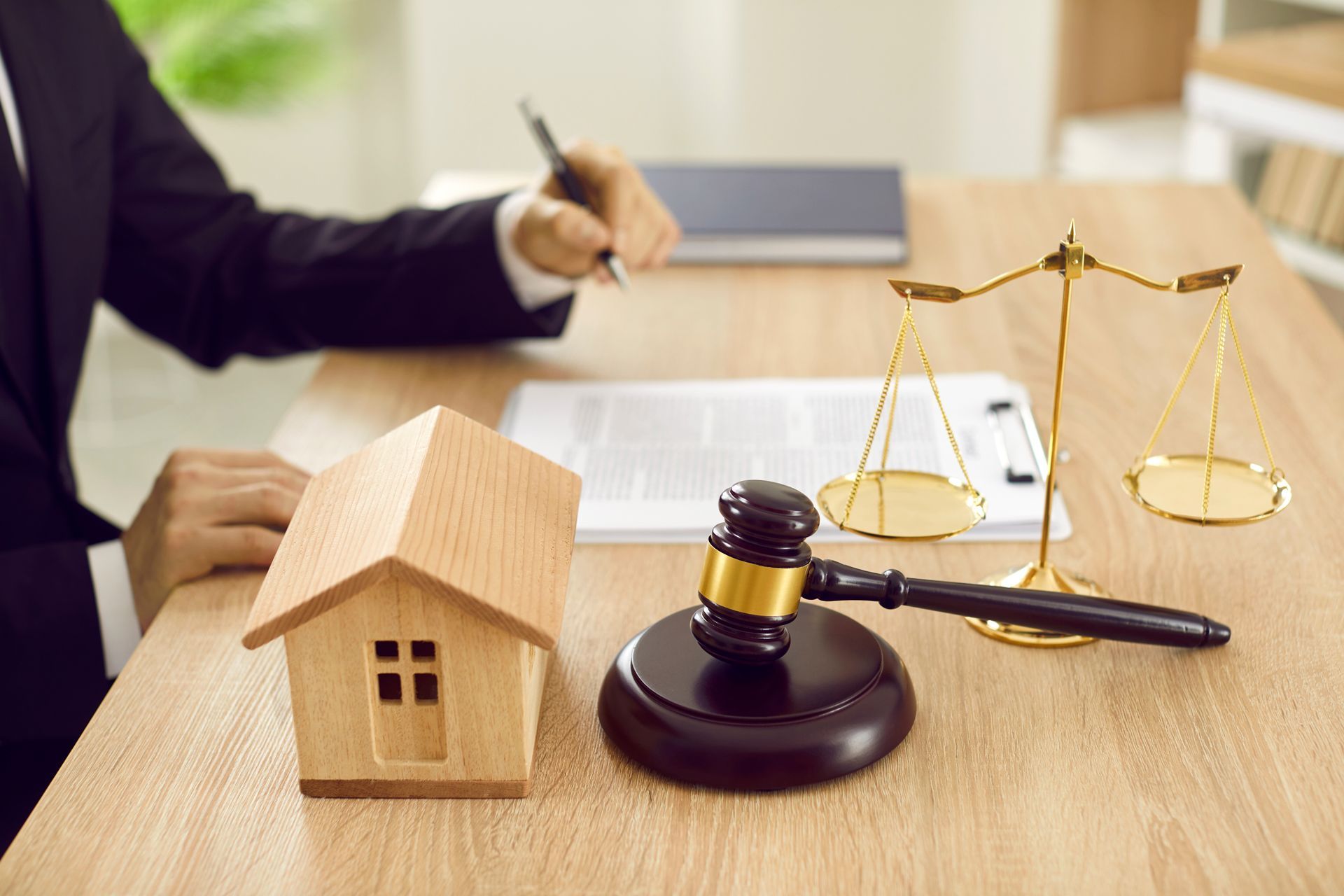 Lawyer's desk with house model, gavel, scales of justice, and documents