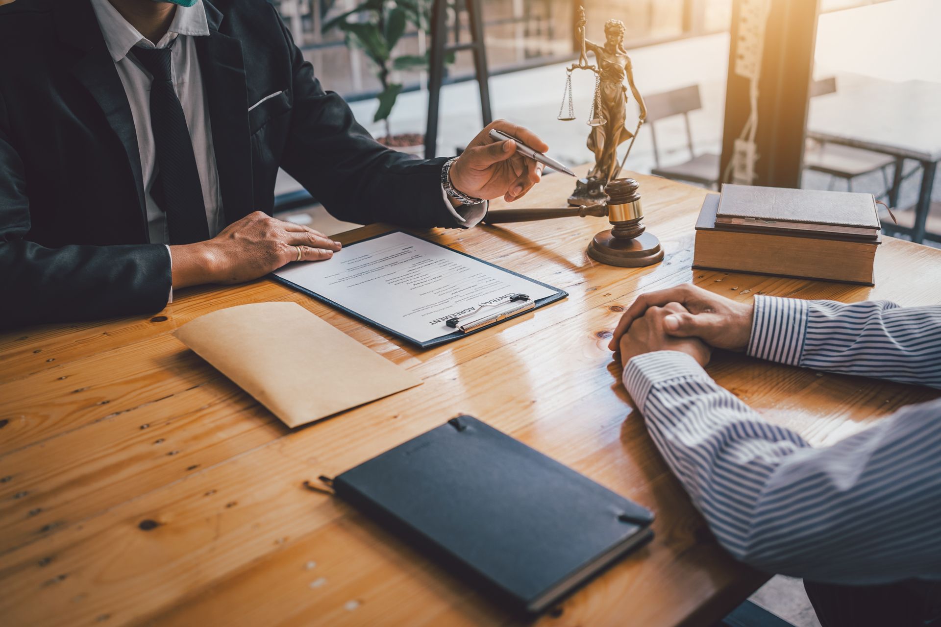 Business meeting at a wooden table with documents, books, and a gavel in a sunlit office