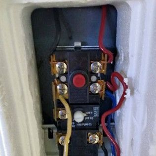Close-up of an electrical relay or switch with red and yellow wires inside a white enclosure