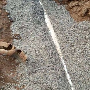 Close-up of gravel road with a white painted line and muddy edges