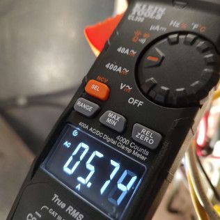 Digital multimeter showing 05.79 on its backlit display, with selector knob visible.