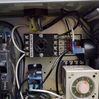 Close-up of an electrical control panel with wires, terminal blocks, and a white timer dial.