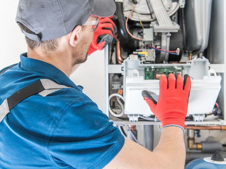 Technician in red gloves repairing electrical equipment inside an industrial machine cabinet