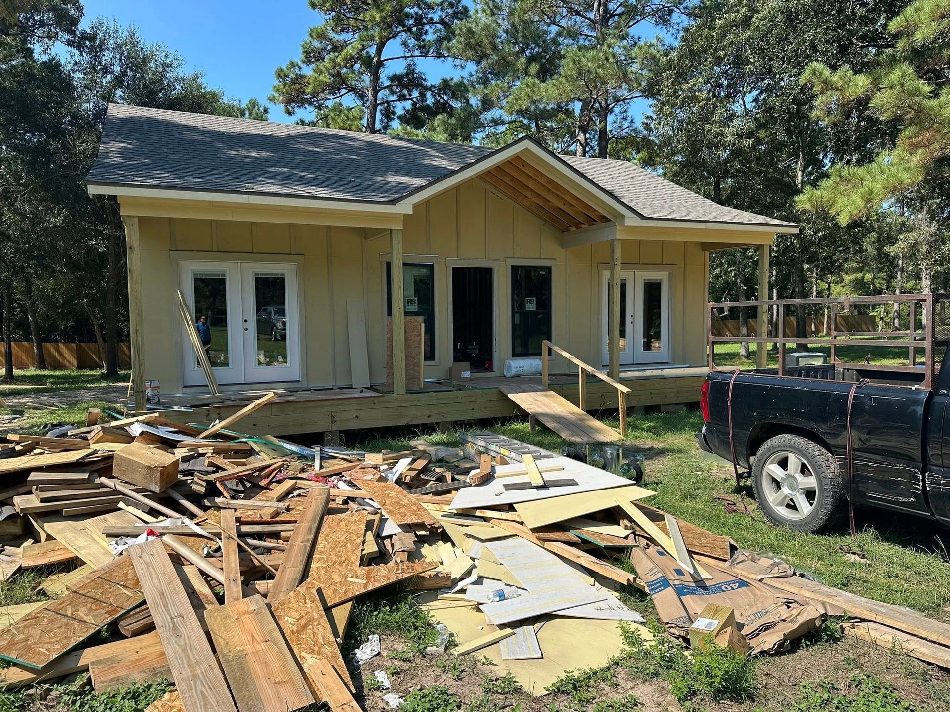 House under construction with debris in foreground; a truck is parked nearby.