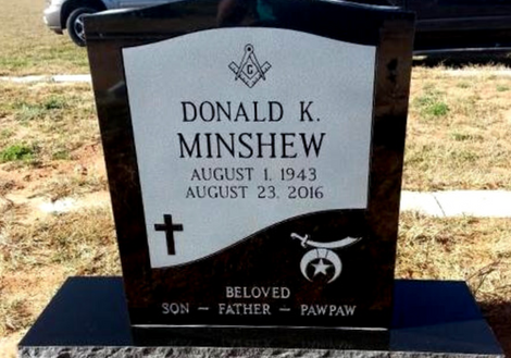 Black-and-white memorial headstone for Donald K. Minshew with cross and eagle emblem outdoors