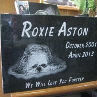 Memorial plaque for Roxie Aston with dog portrait and dates, “October 2001–April 2013,” “We Will Love You Forever”