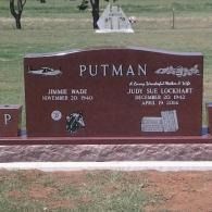 Maroon gravestone memorial with white lettering in a cemetery, reading “PUTMAN.”