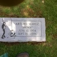 Gravestone plaque on grass with engraved name, dates, and a fisherman silhouette graphic