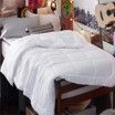 A bed with a white blanket on it in a room.