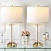 A pair of table lamps sitting on top of a glass table next to a vase of flowers.