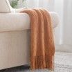 A brown blanket is sitting on a white couch.