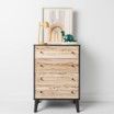 A wooden chest of drawers with a picture on top of it.
