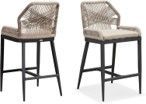 A pair of wicker bar stools on a white background.