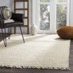 A white rug is sitting on the floor in a living room next to a chair.