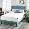 A bed with a blue headboard is sitting in a bedroom next to a window.