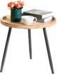 A small table with a vase of flowers , a cup , and a book on it.