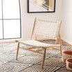 A chair is sitting on a rug in a living room next to a window.