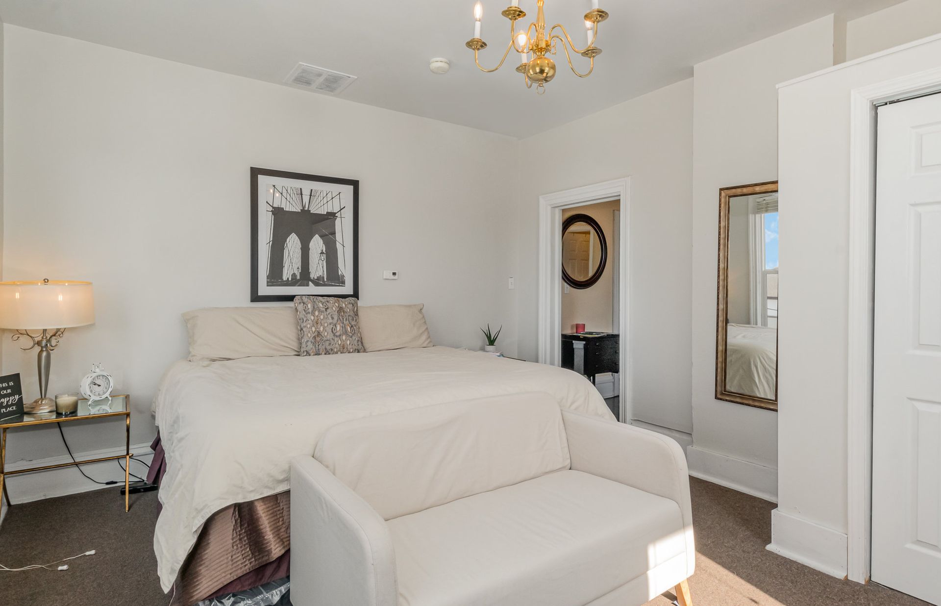 A bedroom with a bed , chair , and mirror.