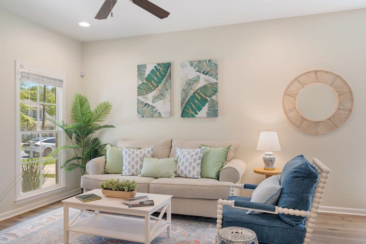 A living room with a couch , chair , coffee table and ceiling fan.