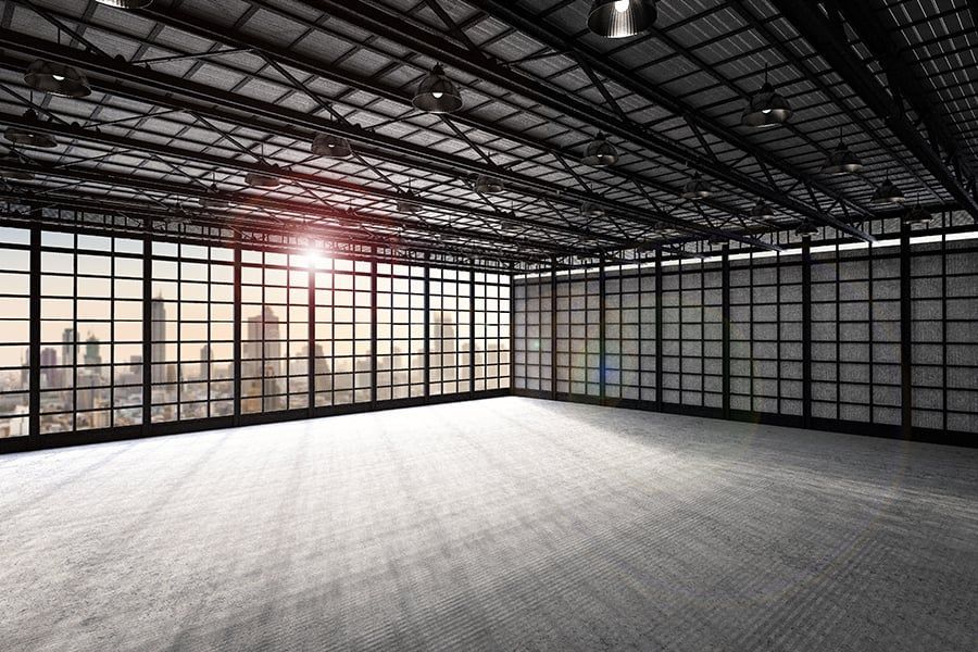 An empty room with a lot of windows and a view of the city.