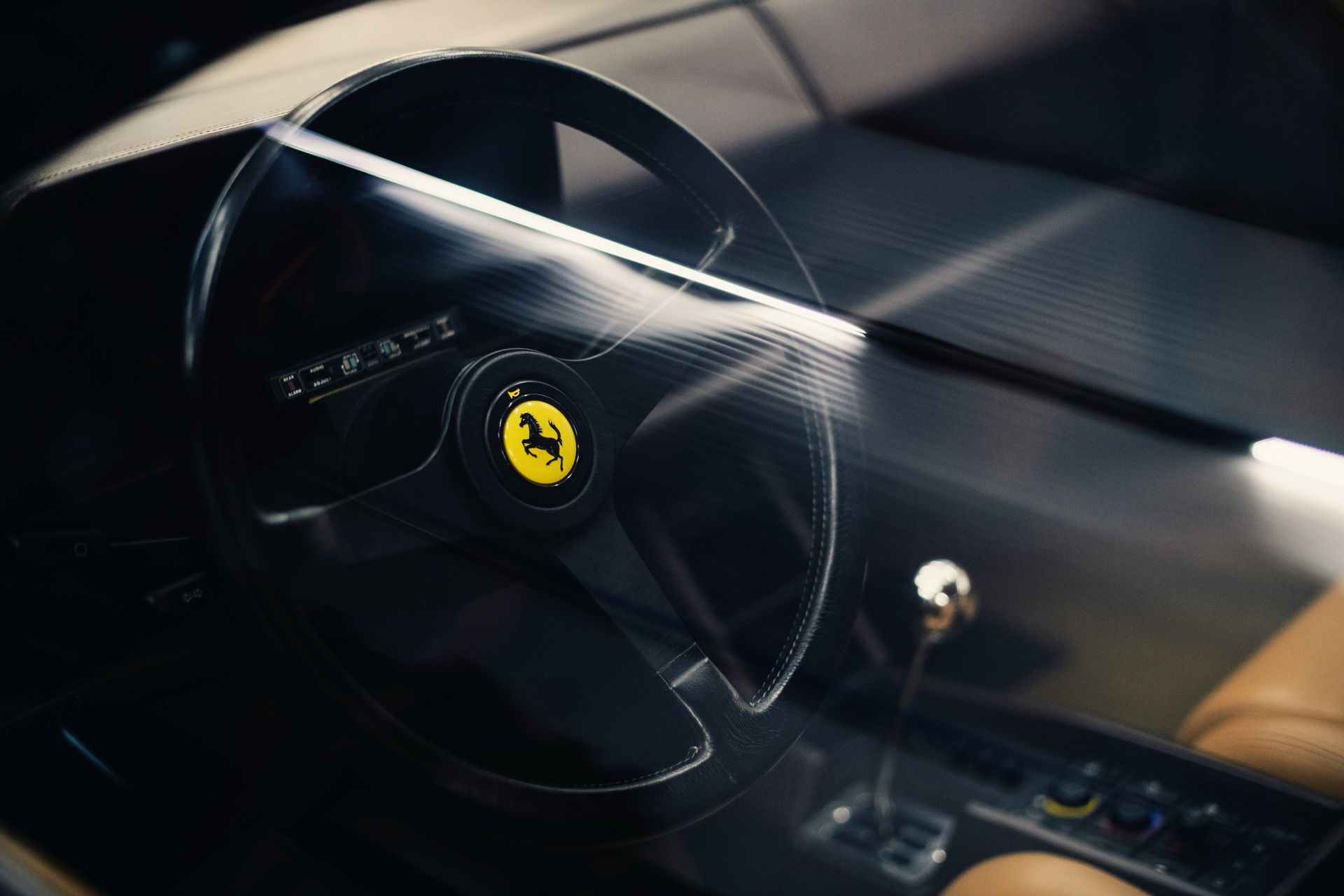 Ferrari steering wheel and dashboard in a sleek black sports car interior