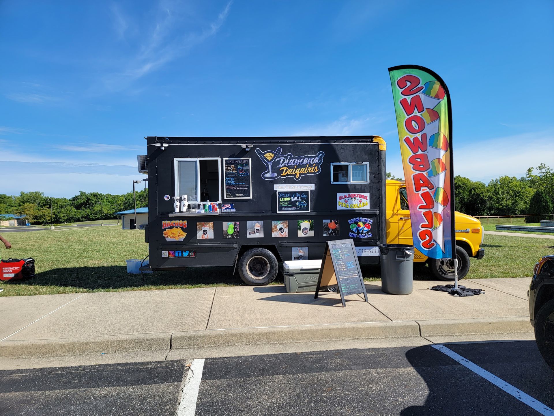 A food truck is parked on the side of the road in a parking lot.
