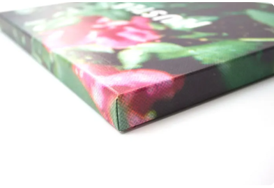 Detailopname van een opgespannen canvasprint, met een hoek in beeld. Bloemenmotief in roze en groen.
