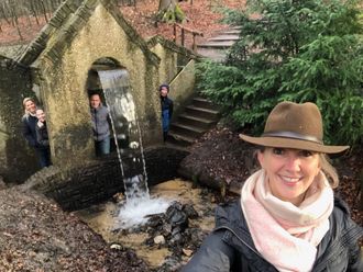 selfie bij een waterval van steen, anderen poseren in de buurt. 