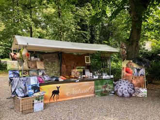 Marktkraam onder een luifel. Er worden tassen, textiel en decoratieve artikelen aangeboden. 