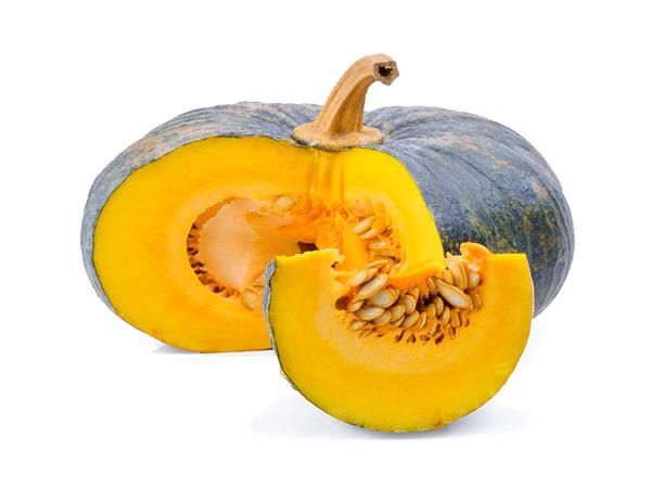 Cut open kabocha squash with bright orange flesh, seeds, and dark green rind.