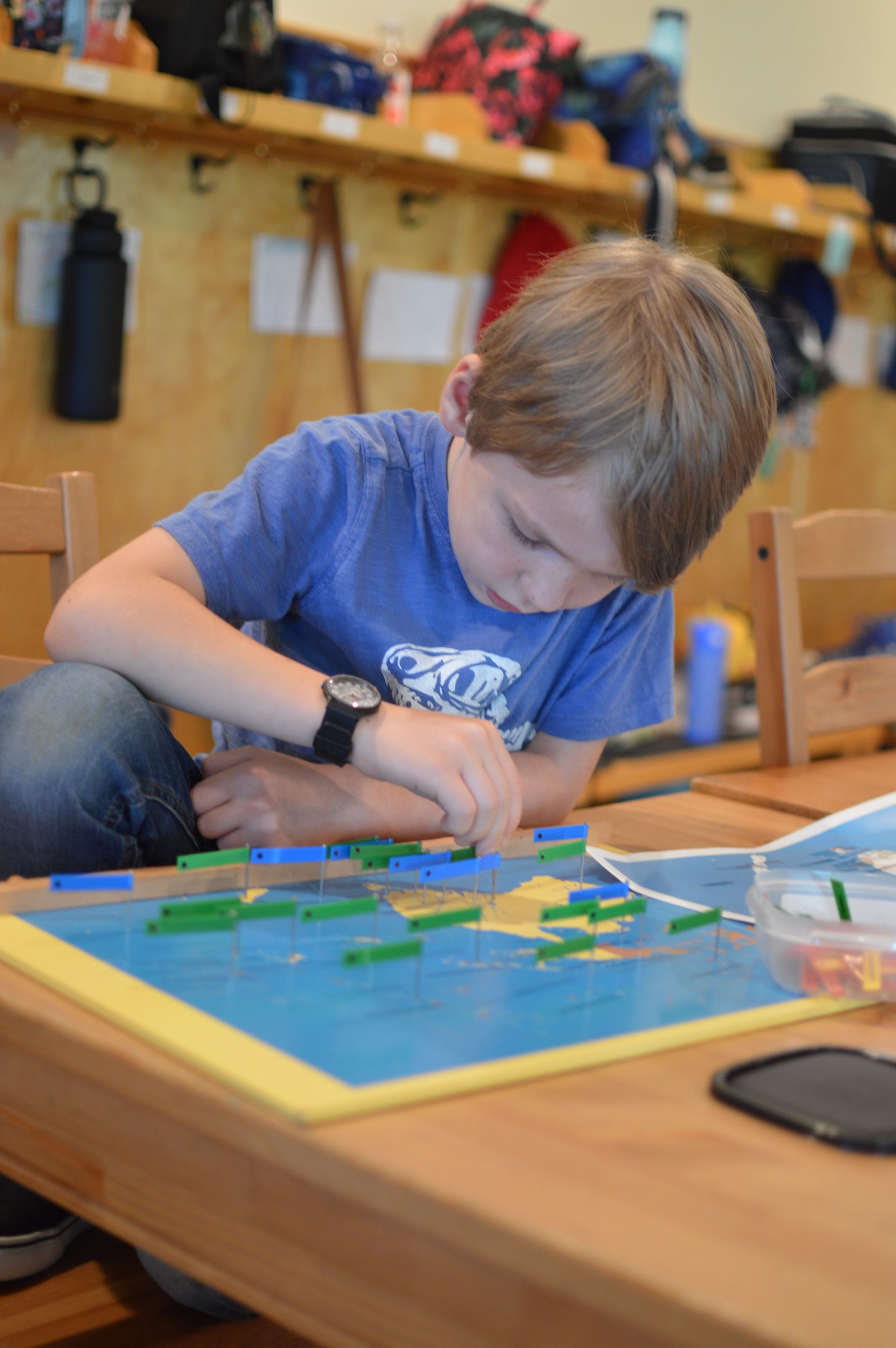 Montessori child working with green and blue blocks on a table. Classroom setting.