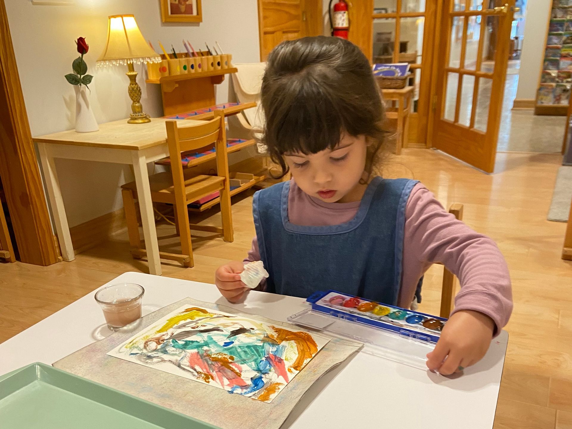 Child painting at a table in a cozy home, focused on colorful artwork.