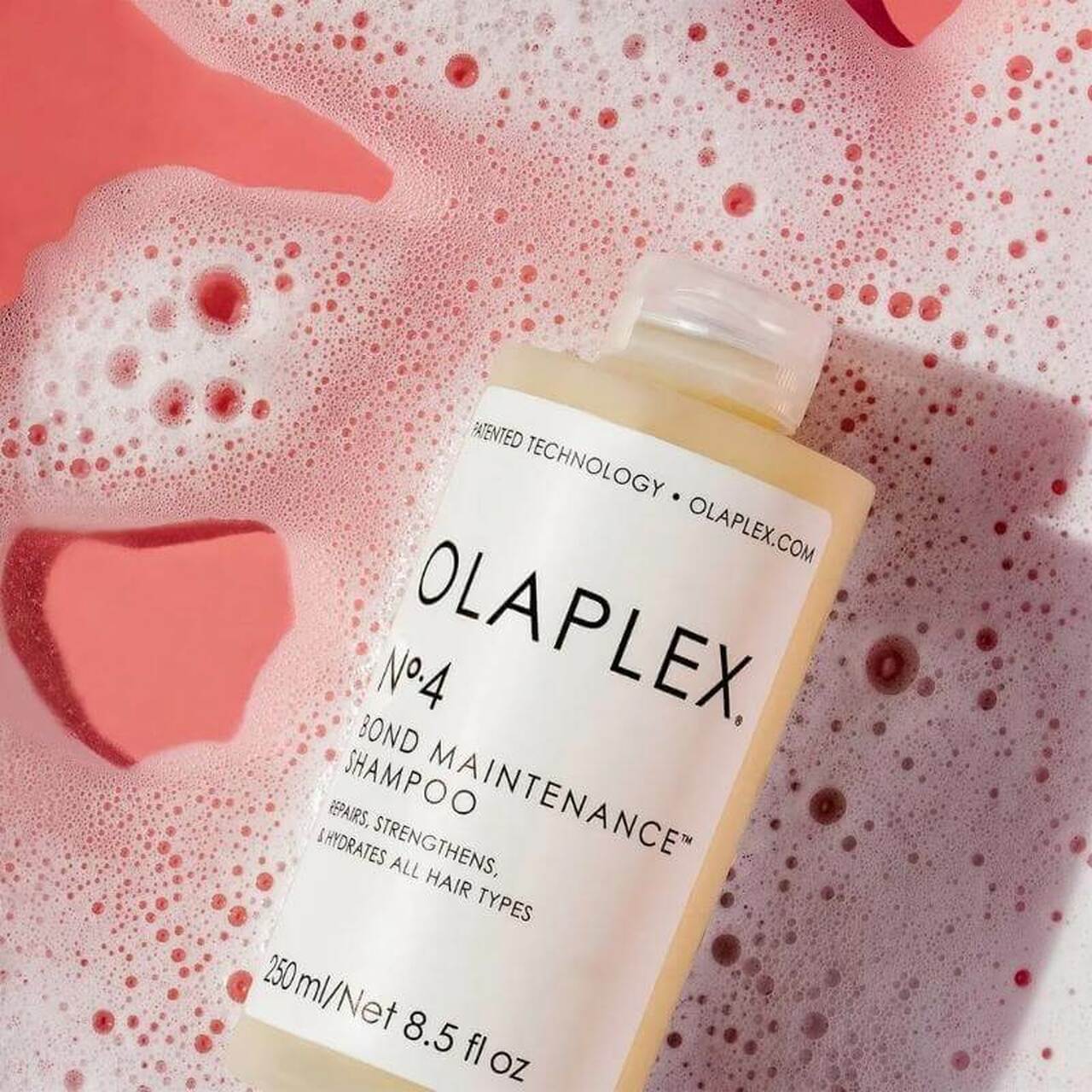 Fles Olaplex No. 4 Bond Maintenance Shampoo in zeepwater met roze tinten.
