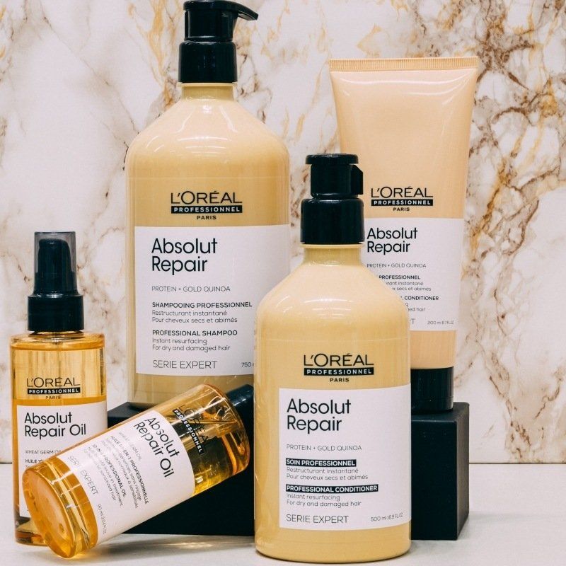 L'Oréal Absolut Repair haarproducten in diverse flessen en verpakkingen op een marmeren ondergrond.